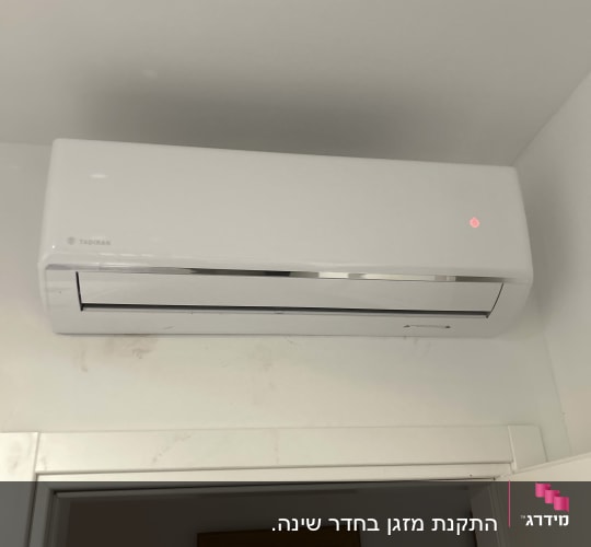 מזגן קיר לבן מותקן מעל דלת